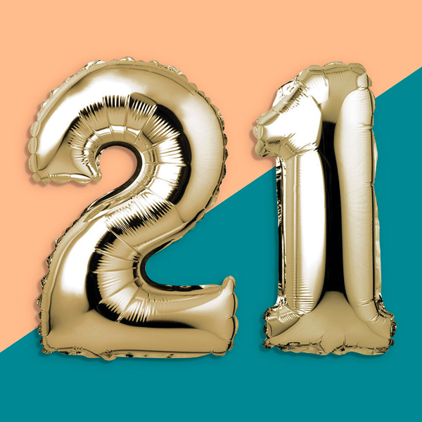 Two gold, mylar balloons numbered two and one appear side by side to create the number twenty-one.