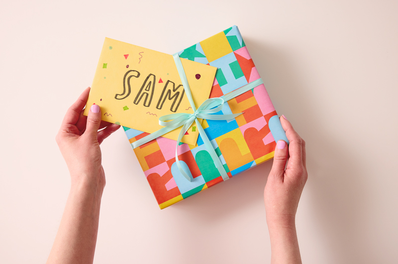 A woman slides a yellow envelope with handlettering that reads 