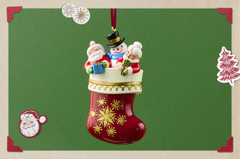 A Keepsake Ornament in the shape of a deep red Christmas stocking embroidered with gold snowflakes; tucked inside the stocking are Santa and Mrs. Claus, as well as Frosty the Snowman.