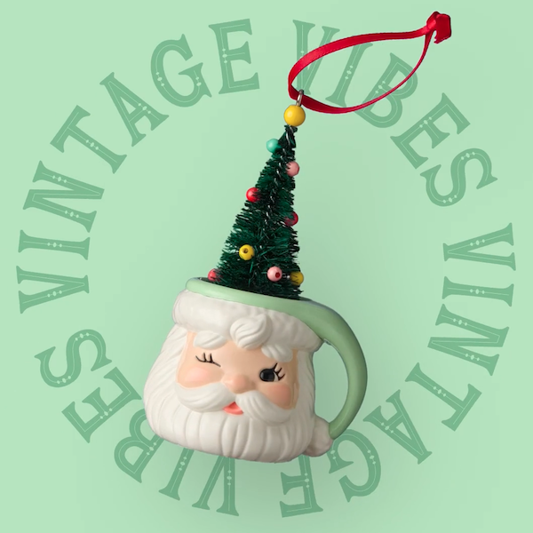 A Christmas ornament in the shape of a figural Santa mug with a hat made of a bottle brush Christmas tree appears super-imposed on a light green background with the words, 